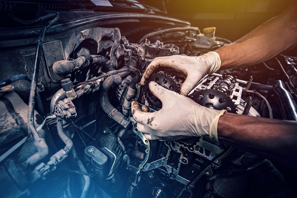 Mechanic repairing a car engine with gloves on.